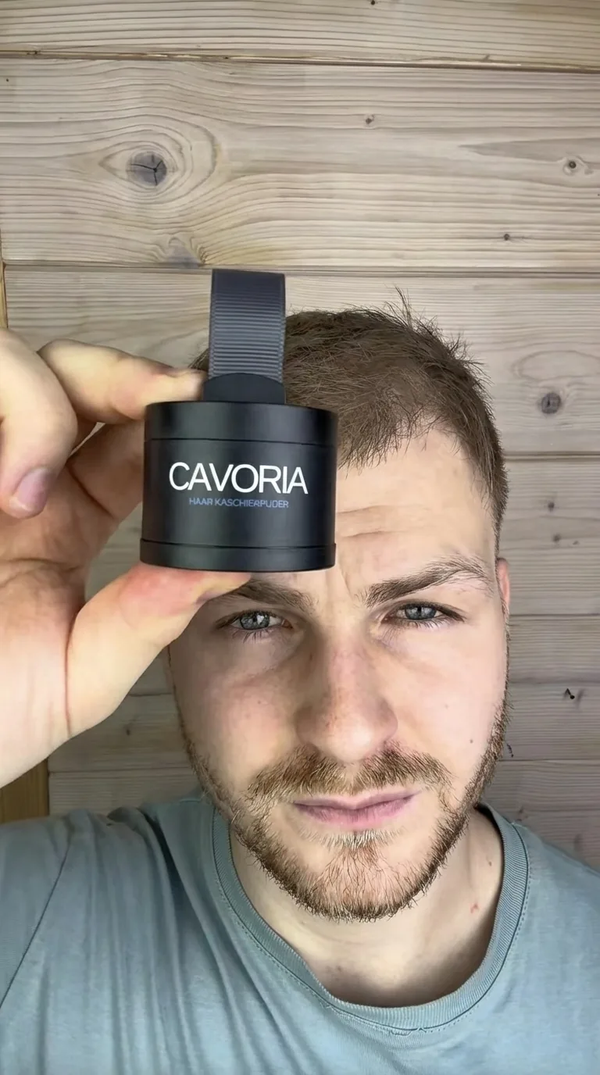 Mann zeigt CAVORIA Haar Kaschierpuder – Kunde hält schwarze Dose mit Applikator vor Holzhintergrund